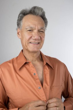 Yetişkin kıdemli adam iş için giyinirken gömleğini ilikliyor. 