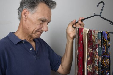 Olgun bir kıdemli adam kravat seçmeye çalışıyor.