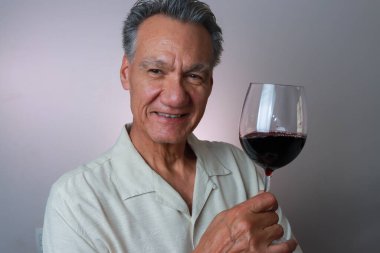 Olgun Adam elinde büyük bir kadeh kırmızı şarap tutuyor.