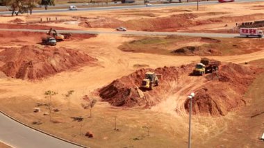 Brasilia, DF, Brezilya 25 Temmuz 2024 Kazıcı, kuzeybatı Brasilia 'da yeni bir yol yapmak için toprağı kazıyor ve bir çöp kamyonuna toprak yüklüyor