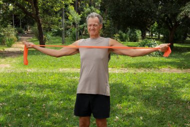 Hareket kabiliyeti ve dayanıklılığı arttırmak için spor bandı ya da elastik bant kullanan olgun bir adam.   