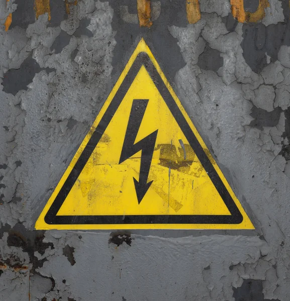 高電圧サイン ラスティグレー塗装金属表面上の黄色の三角形の黒い矢印 — ストック写真