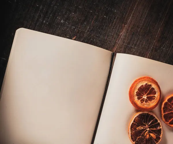 Sanat ve yaratıcı ilham için kurumuş portakal dilimleriyle birlikte açık bir defter..