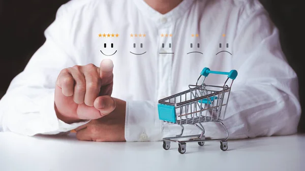 Man give rating five star and smiley face symbold, satisfaction concept marketing, shopping cart on white table.
