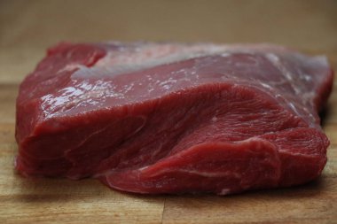 Ahşap bir mutfak doğrama tahtasının üzerinde kesilmiş kırmızı et parçası. Yüksek kalite fotoğraf