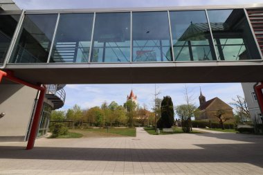 HAAG, GERMANY - 20 Nisan 2025: Oberbayern 'deki Realschule Haag' ın iki binasını birbirine bağlayan cam kaplı yaya köprüsü, kırmızı yapısal unsurlar tarafından desteklenmektedir. Yüksek kalite fotoğraf