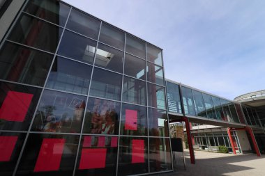 HAAG, GERMANY - 20 Nisan 2025: Oberbayern 'deki Realschule Haag' ın iki binasını birbirine bağlayan cam kaplı yaya köprüsü, kırmızı yapısal unsurlar tarafından desteklenmektedir. Yüksek kalite fotoğraf