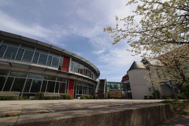 HAAG, GERMANY - 20 Nisan 2025: Oberbayern 'deki Realschule Haag' ın iki binasını birbirine bağlayan cam kaplı yaya köprüsü, kırmızı yapısal unsurlar tarafından desteklenmektedir. Yüksek kalite fotoğraf