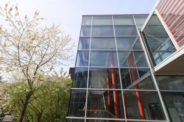 HAAG, GERMANY - 20 Nisan 2025: Oberbayern 'deki Realschule Haag' ın iki binasını birbirine bağlayan cam kaplı yaya köprüsü, kırmızı yapısal unsurlar tarafından desteklenmektedir. Yüksek kalite fotoğraf