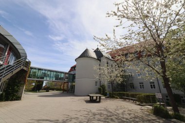 HAAG, GERMANY - 20 Nisan 2025: Oberbayern 'deki Realschule Haag' ın iki binasını birbirine bağlayan cam kaplı yaya köprüsü, kırmızı yapısal unsurlar tarafından desteklenmektedir. Yüksek kalite fotoğraf