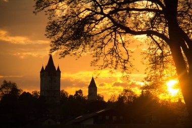 HAAG, GERMANY - 14 Mayıs 2013: Schlossturm ve Kleiner Schlossturm in Haag in Oberbayern 'in günbatımı, canlı turuncu ve sarı bir gökyüzüne karşı siluet