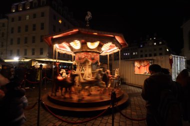 DRESDEN, GERMANY - 20 Aralık 2024: Geleneksel Striezelmarkt Noel pazarında, ziyaretçilerin festival atmosferinin tadını çıkardıkları parlak ışıklı bir atlıkarınca. Yüksek kalite fotoğraf