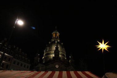 DRESDEN, Almanya - 20 ARALIK 2024: Yılbaşı pazarı çatısı ve gece Striezelmarkt 'taki Frauenkirche Kubbesi. Yüksek kalite fotoğraf