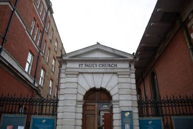 LONDON, İngiltere - 30 Aralık 2017: Londra 'da St Pauls Kilisesi' nin girişi, tuğla binalar tarafından çerçevelenmiş üçgen bir pedikür ve sütunlar da dahil olmak üzere klasik mimari unsurları içerir. Yüksek