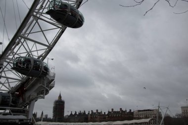 Londra Göz Kapsülleri 'nin dramatik görüntüsü ve Westminster Sarayı ve Big Ben' le birlikte bulutlu bir kış gökyüzünün altında destekleyici yapı. Yüksek