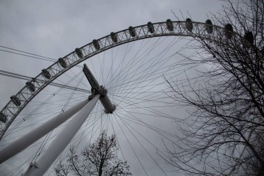 LONDON, UNITED KINGDOM - 30 ARALIK 2017: Londra Gözü 'nün geniş açılı görüntüsü ve bulutlu bir gökyüzü altında sahneyi çevreleyen çıplak ağaç dalları. Yüksek kalite fotoğraf