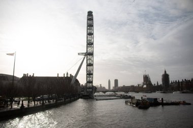LONDON, UNITED KINGDOM - 30 ARALIK 2017: Uzakta ikonik binaların siluetleriyle sisli bir gökyüzünün altında Londra Gözü ve Thames Nehri manzarası. Yüksek kalite fotoğraf