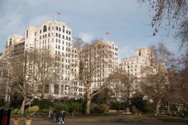 LONDON, UNITED KINGDOM - 30 ARALIK 2017: Çağdaş mimarisi olan modern beyaz konut binaları kentsel gelişim alanındaki çıplak kış ağaçları aracılığıyla görülüyor. Yüksek kalite fotoğraf