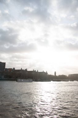 Londra, BİRLİK KINGDOM - 30 Aralık 2017: dramatik bulutlu bir gökyüzü altında Thames Nehri 'nin görüntüsü, liman boyunca silueti olan binalar ve sudan yansıyan güneş ışığı. Yüksek kalite