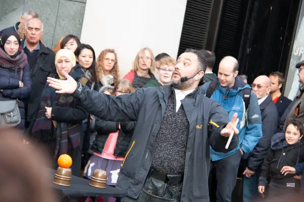 Londra, UNITED KINGDOM - 30 Aralık 2017: Bir sokak sanatçısı Covent Garden 'da bir hokkabazlık gösterisiyle kalabalığa karışıyor, seyirciler gösteriyi kamusal alanda izliyor. Yüksek kalite fotoğraf