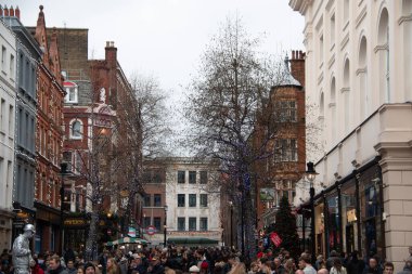 LONDON, UNITED KINGDOM - 30 ARALIK 2017: Covent Garden 'daki yayalar, yapraksız kış ağaçları ve klasik İngiliz mimarisi arasında yürüyen büyük kalabalıklar.