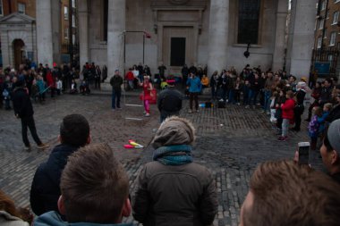 LONDON, UNITED KINGDOM - 30 ARALIK 2017: Sokak sanatçısı Londra şehir merkezindeki bir kış günü klasik mimarinin yakınındaki tarihi bir kaldırım taşı plazasında büyük bir kalabalığı eğlendiriyor. Yüksek kalite