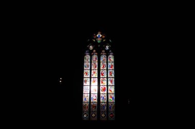 COLOGNE, ALMANY - 29 Aralık 2017 Köln Katedrali 'nin karanlığında parlayan izole cam pencere Gotik çerçevede canlı dini imgeleri vurguluyor. Yüksek kalite fotoğraf