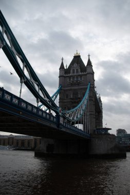 LONDON, UNITED KINGDOM - 30 ARALIK 2017: Thames Nehri 'ne açılı bir perspektiften yakalanan Kule Köprüsü, Gotik Diriliş kulelerini ve bulutlu bir buluta karşı süspansiyon unsurlarını vurguluyor