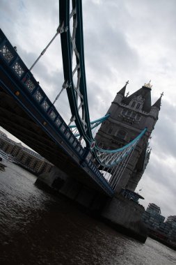 LONDON, UNITED KINGDOM - 30 ARALIK 2017: Thames Nehri 'ne açılı bir perspektiften yakalanan Kule Köprüsü, Gotik Diriliş kulelerini ve bulutlu bir buluta karşı süspansiyon unsurlarını vurguluyor