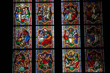 COLOGNE, ALMANY - 29 Aralık 2017: Köln Katedrali 'nin içindeki karmaşık boyalı cam panellere yakın çekim, İncil' deki canlı sahneler ve yumuşak ortam ışığı altında Gotik desenler sergiliyor. Yüksek