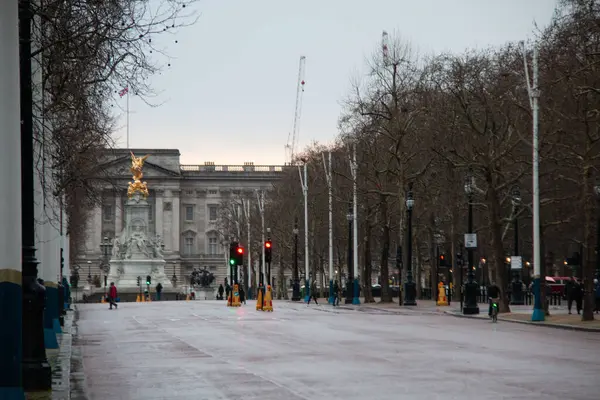 LONDON, BİRLİK KINGDOM - 23 ARALIK 2017: Soğuk bir kış günü, Buckingham Sarayı ve Victoria Anıtı 'na uzak bir manzara, yol boyunca çıplak ağaçlar ve az sayıda yayayla kaplı