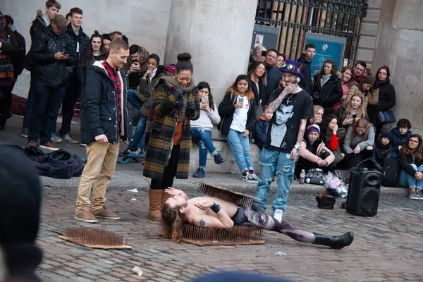 BİRLİK KINGDOM - 30 ARALIK 2017: Bir kadın sanatçı yerde yatarken, tarihi Covent Garden Marketi önünde dramatik bir sokak gösterisi etrafında bir kalabalık toplanıyor.