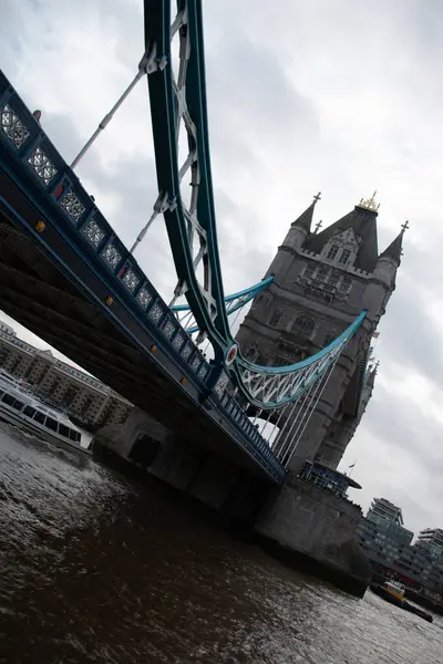LONDON, UNITED KINGDOM - 30 ARALIK 2017: Thames Nehri 'ne açılı bir perspektiften yakalanan Kule Köprüsü, Gotik Diriliş kulelerini ve bulutlu bir buluta karşı süspansiyon unsurlarını vurguluyor