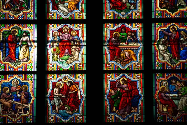 COLOGNE, ALMANY - 29 Aralık 2017: Köln Katedrali 'nin içindeki karmaşık boyalı cam panellere yakın çekim, İncil' deki canlı sahneler ve yumuşak ortam ışığı altında Gotik desenler sergiliyor. Yüksek