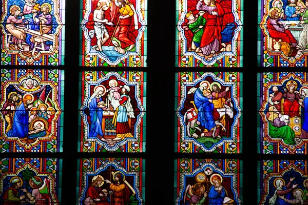 COLOGNE, ALMANY - 29 Aralık 2017: Köln Katedrali 'nin içindeki karmaşık boyalı cam panellere yakın çekim, İncil' deki canlı sahneler ve yumuşak ortam ışığı altında Gotik desenler sergiliyor. Yüksek