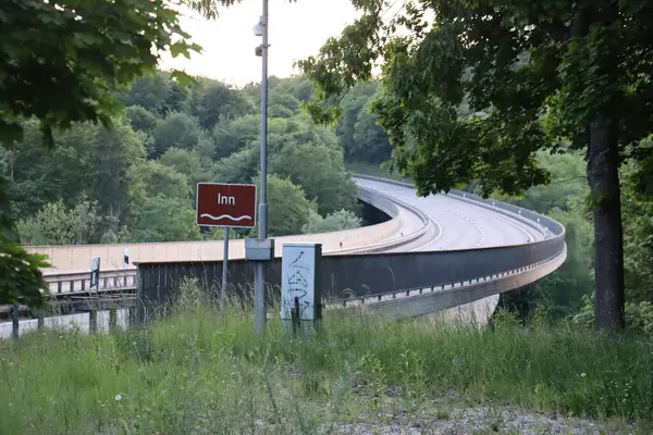 WASSERBURG, ALMANY - 19 Mayıs 2025: Innbruecke köprüsü yakınlarındaki kahverengi nehir tabelası çevresindeki ağaçlar ve yol altyapısı ile işaretlendi. Yüksek kalite fotoğraf