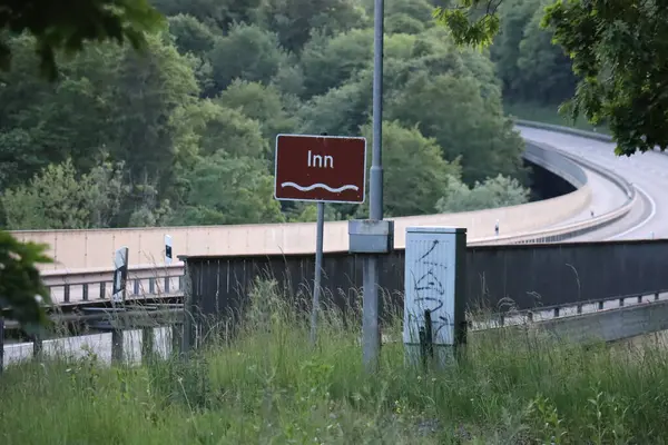 WASSERBURG, ALMANY - 19 Mayıs 2025: Innbruecke köprüsü yakınlarındaki kahverengi nehir tabelası çevresindeki ağaçlar ve yol altyapısı ile işaretlendi. Yüksek kalite fotoğraf