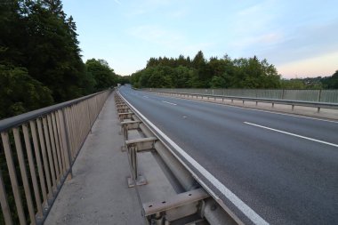 WASSERBURG AM Hanı, ALMANY - 19 Mayıs 2025: Wasserburg yakınlarındaki içi boş Innbruecke köprüsü, gün batımında demir parmaklıklar ve orman kaplı yollar. Yüksek kalite fotoğraf