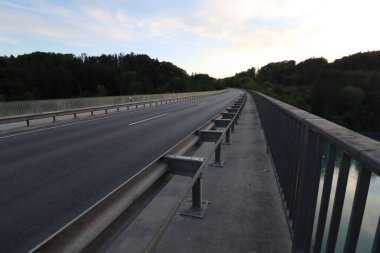 WASSERBURG AM Hanı, GERMANY - 19 Mayıs 2025: Orman tepeleri ve yumuşak akşam gökyüzü ile çevrili Innbruecke Köprüsü 'nün yaya ve trafik şeritlerinin görüntüsü. Yüksek kalite fotoğraf