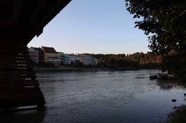WASSERBURG AM Hanı, GERMANY - 30 Mayıs 2025: Inn Nehri 'nin doğu manzarası ve Innbruecke Köprüsü' nün altından gün batımında Wasserburg am Inn 'in binaları. Yüksek kalite fotoğraf
