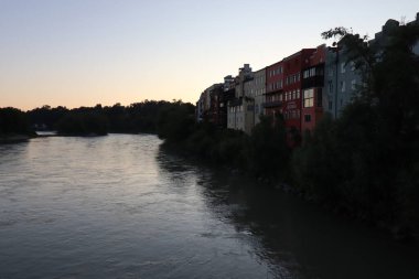 WASSERBURG AM Hanı, ALMANY - 30 Mayıs 2025: Akşam manzarası nehir kenarındaki renkli binalar ve gün batımında Inn Nehri boyunca ağaçlarla kaplı kıyılar. Yüksek kalite fotoğraf