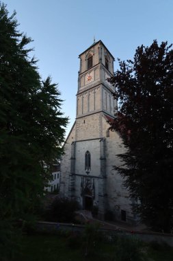 WASSERBURG AM Hanı, ALMANY - 30 Mayıs 2025: Wasserburg am Inn 'in tarihi merkezinde ağaçlar ve yeşilliklerle çevrili Sankt Jakob Kilisesi' nin akşam manzarası. Yüksek kalite fotoğraf