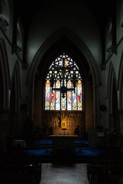 SHREWSBURY, UNITED KINGDOM - 2 Ocak 2018: Shrewsbury 'deki St Alkmunds Kilisesi' nin koyu iç manzarası büyük bir vitray penceresi ve mihrabın üzerinde Gotik kemer. Yüksek kalite fotoğraf