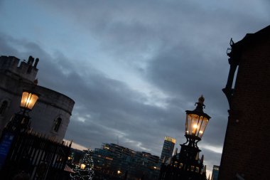 LONDON, UNITED KINGDOM - 1 HAZİRAN 2018: Londra Kulesi yakınlarında tarihi mimari, aydınlatma fenerleri ve şehrin üzerinde dramatik gece bulutları bulunan alacakaranlık manzarası. Yüksek kalite fotoğraf