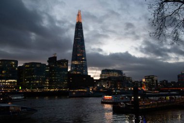 LONDON, UNITED KINGDOM - 1 Ocak 2018 Londra 'nın Çömlek Parçası ile aydınlanmış silueti ve dramatik akşam bulutları altında Thames Nehri' nin yansımaları. Yüksek kalite fotoğraf