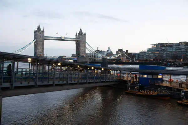 LONDON, UNITED KINGDOM - 1 HAZİRAN 2018: Thames Nehri üzerinde yansımaları olan nehir kenarındaki bir gezinti alanından Tower Bridge 'in gündüz görüşü ve ön plandaki modern yürüme yolları. Yüksek kalite fotoğraf