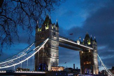 LONDON, BİRLİK KINGDOM - 1 HAZİRAN 2018 Kule Köprüsü 'nün gece görüşü derin mavi bir gökyüzü ve gezinti alanındaki sahneyi çevreleyen ağaç dallarıyla tamamen aydınlandı. Yüksek kalite fotoğraf