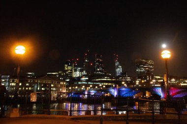 LONDON, UNITED KINGDOM - 1 HAZİRAN 2018 Blackfriars Demiryolu Köprüsü ve Londra şehrinin gece gökyüzü manzarası Thames Nehri 'ndeki yansımaları ve parlayan sokak lambalarıyla aydınlandı