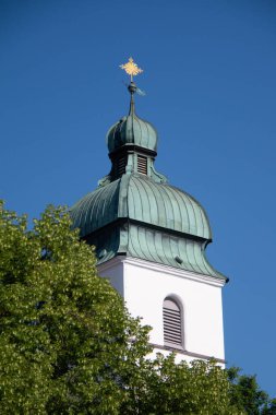 EBERSBERG, GERMANY - 8 Mayıs 2018: Ebersberg 'deki yeşil ağaçların üzerinde yükselen Katolik kilisesinin barok kilise kulesinin manzarası. Yüksek kalite fotoğraf