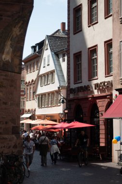 Heidelberg 'in eski kasabasında, geleneksel yarı ahşap ve sıva binaları, açık havada oturma yerleri ve güneşli bir günün tadını çıkaran insanlar. Yüksek